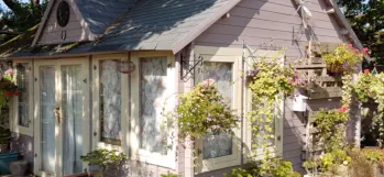 A wooden building with hanging baskets and flowers used for relaxation at  our horticulture and conservation project